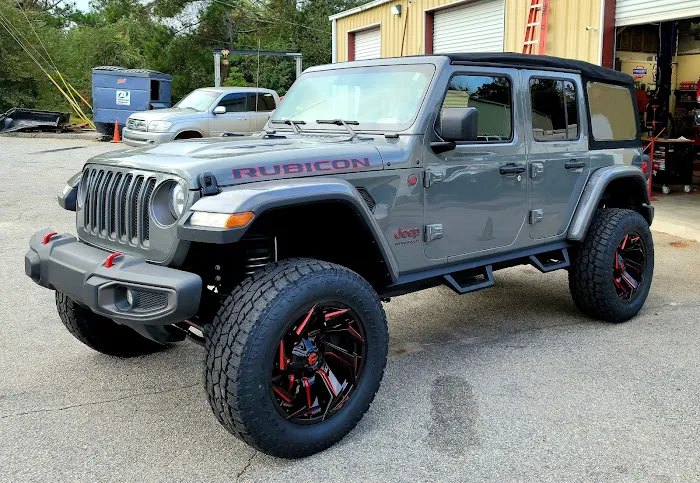 Jeep Wrangler Rubicon with aftermarket wheels and all-terrain tires at the shop