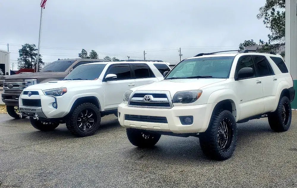 Two lifted white Toyota 4Runners with aftermarket wheels at Automotive Highlights